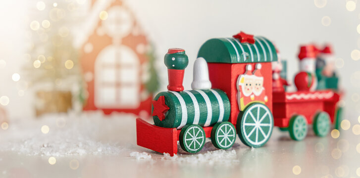 A red and green train stands on the snow on light background. Christmas and New Year celebration concept, background