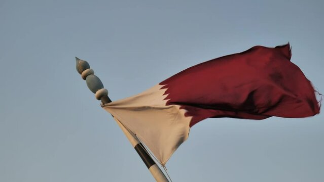 Scenic view of the Qatar red and white flag fluttering in the wind with blue sky in the background
