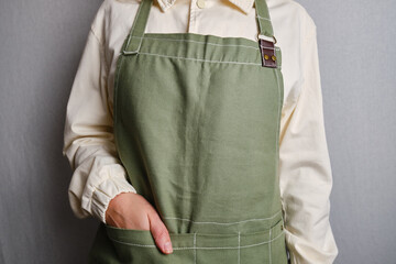 A woman in a kitchen apron. Chef work in the cuisine. Cook in uniform, protection apparel. Job in food service. Professional culinary. Green fabric apron, casual clothing. Handsome baker posing
