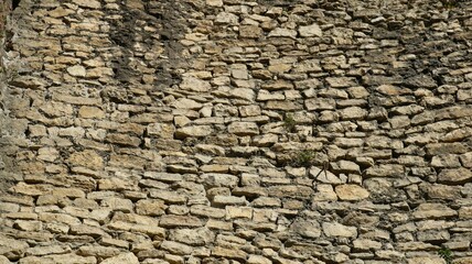graphic resource of uneven cobblestone wall of old fortress, picture full frame, stone texture with irregular pattern and relief in gray-brown shade, ancient boulder wall as wallpaper