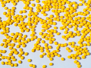 Yellow masterbatch granules in a glass cup isolated on a white background, with colorchips as the resulting color sample, masterbatch is a coloring agent for plastic industry products