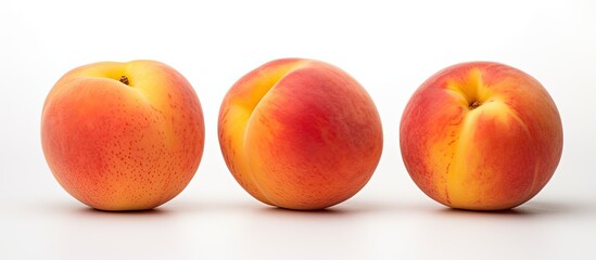 Fototapeta na wymiar There are three fully developed peaches resting on a background that is white in color