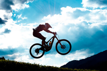 Mountain Bike Downhill Fahrer im Gegenlicht bei Sprung während Wettkampf – MTB Rider Jumping Silhouette - obrazy, fototapety, plakaty