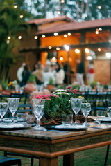 outdoor dining, sophisticated event, crystal glassware, polished plates, rustic centerpiece, wooden decor, potted herbs, table setup, celebration, elegant