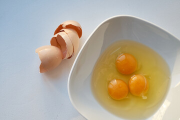 Bowl of raw eggs and eggshells on white background. Eggs are a healthy food