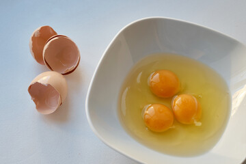 Bowl of raw eggs and eggshells on white background. Eggs are a healthy food
