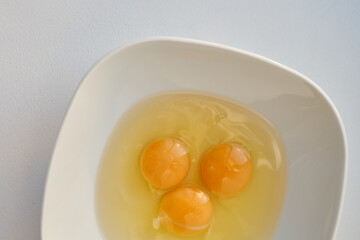 Bowl of raw eggs and eggshells on white background. Eggs are a healthy food
