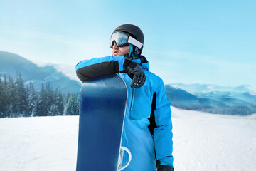 Snowboarder Of Man At Ski Resort On The Background Blue Sky,  Hold Snowboard. Wearing Ski Glasses. Ski Goggles  With The Reflection Of Snowed Mountains