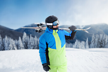 Fototapeta na wymiar Portrait of a skier in the ski resort on the background of mountains and blue sky, Bukovel. Ski goggles of a man wearing ski glasses. Winter Sports