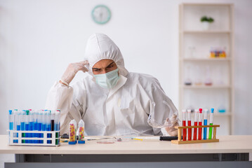 Young male chemist in drugs synthesis concept