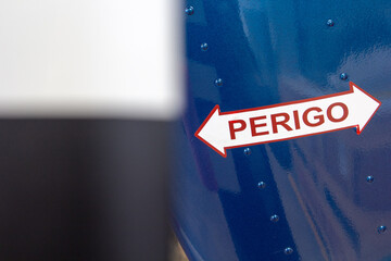 Sign is displayed on a blue background, with the word 'Perigo' written in bold red lettering