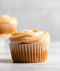 Vanilla cupcake with apple custard cream on blurred concrete background. Vertical shot. Selective focus.