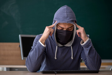 Young male hacker sitting in the classroom