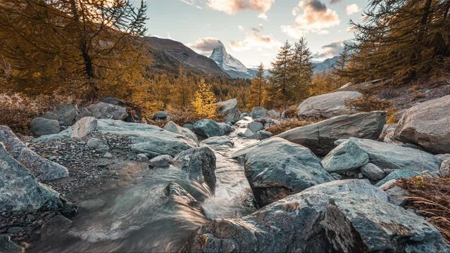Landscape of Matterhorn iconic mountain on golden pine forest and water flowing in the evening at Zermatt, Switzerland