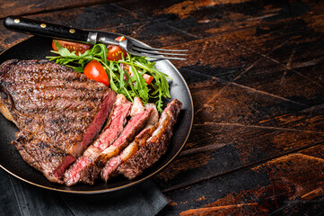 Barbecue grilled and sliced wagyu Rib Eye beef meat steak on a plate. Dark background. Top view....
