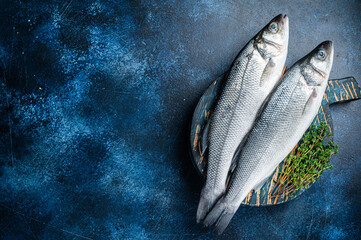 Uncooked Raw Sea Bass fish, Seabass with thyme. Blue background. Top view. Copy space