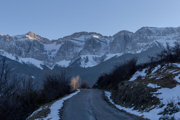 mountain road in winter with snow-capped pines and a large mountain in the background
