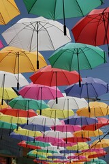 Obraz premium Low angle shot of colorful umbrellas hanging on wire in a narrow city alley
