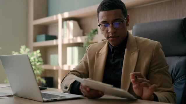 Business man African American accountant male office worker write financial data analysis plan strategy focused businessman work with laptop computer manage project study paper report signing document