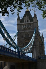 Fototapeta na wymiar Majestic Tower Bridge on the background of the sky with green branches of a tree in the foreground