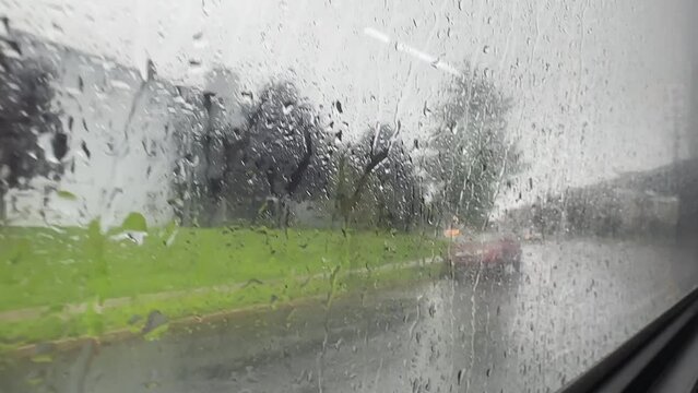 Drops of rain roll down the window of a public Bus traveling along the road