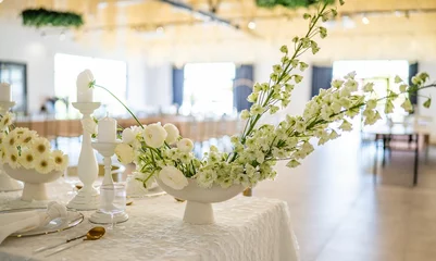Foto op Canvas Closeup of white gerbera flowers in a vase on a white table with candles, ready for an event © Wirestock