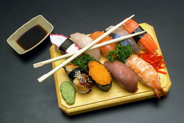 Fototapeta na wymiar Assorted Japanese sushi rolls nigiri, sashimi, maki, salmon, tuna, served on wooden board on dark background
