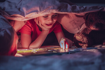 Curious little boy plays an interesting game with a toy instead of sleeping at night