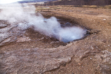 Landscape photo of a hot steamy geyser in the middle of the earth during the cold season