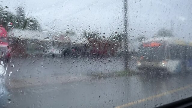 Side window of a bus with raindrops in traffic in the city