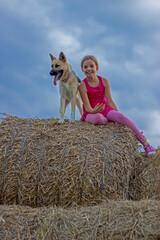 Cute little girl in the field is petting her lovely dog