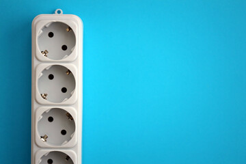 White electrical multi plug extender with european socket on bright blue background close up