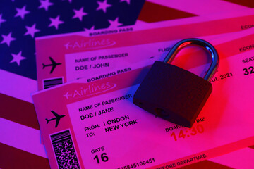 Fictional air tickets and small padlock on United States of America flag close up