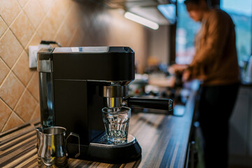 Empty glass stands on the stand of a carob coffee machine on a table against the background of a...