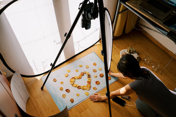 Photographer-stoker lays out patterns from pieces of dried fruits on a blue background. Top view