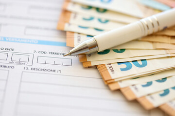 Filling italian tax form process with pen and euro money bills close up. Tax paying period and deadline