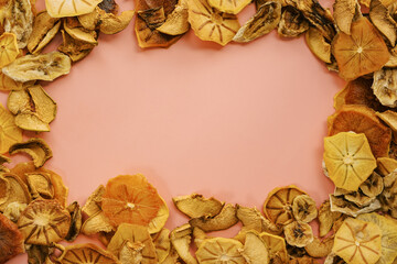 Ornament from pieces of dried fruits on a pink background