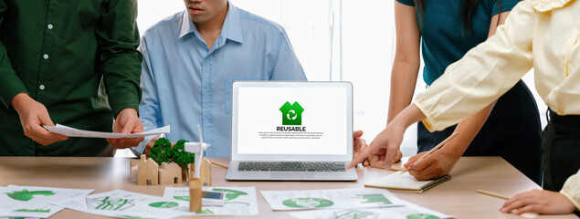 Reusable sign displayed on green business laptop while business team presenting green design to...