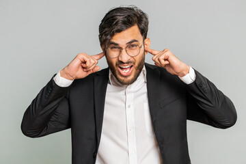 Don't want to hear and listen. Frustrated annoyed irritated Indian businessman covering ears...