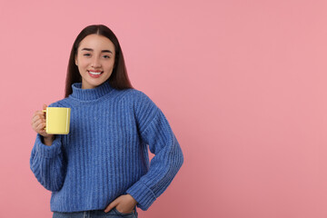 Happy young woman holding yellow ceramic mug on pink background, space for text
