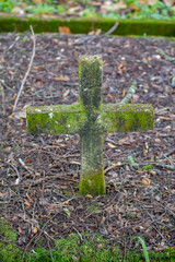 Old forgotten and abandoned cemetery with moss on the cross