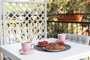 Outdoor breakfast with tea and croissants on white table on terrace