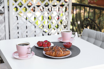 Outdoor breakfast with tea and croissants on white table on terrace