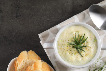 Delicious cream soup with tarragon, spices and potato in bowl served on dark textured table, flat...