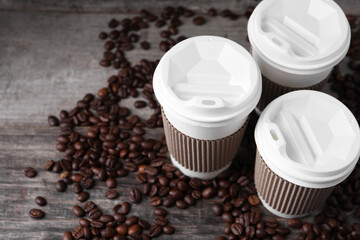 Coffee to go. Paper cups and roasted beans on wooden table, space for text