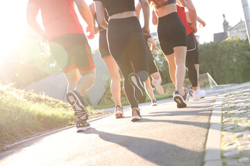 Group of people running outdoors on sunny day, closeup view