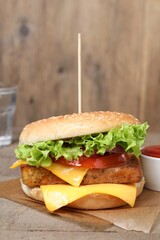Delicious burger with tofu, fresh vegetables and sauce on wooden table