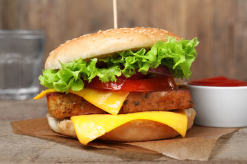 Delicious tofu burger served with sauce on wooden table, closeup