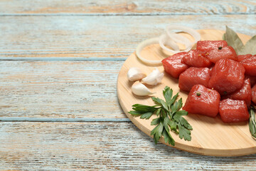 Raw beef meat and different ingredients for cooking delicious goulash on wooden table, space for text
