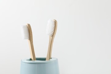 Fototapeta na wymiar Bamboo toothbrushes in holder on white background, closeup. Space for text